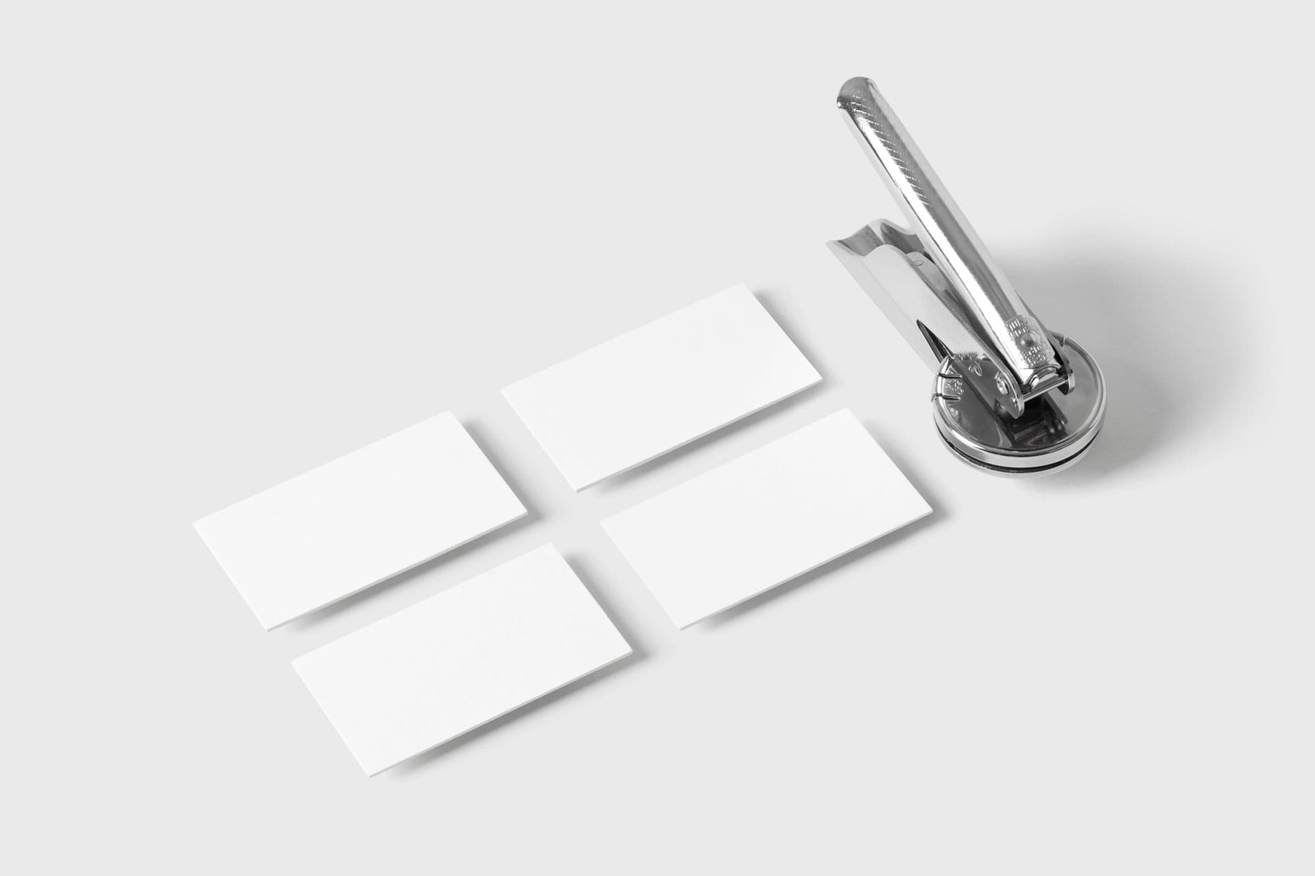 A sleek embosser with blank business cards on a white background, showcasing office essentials.