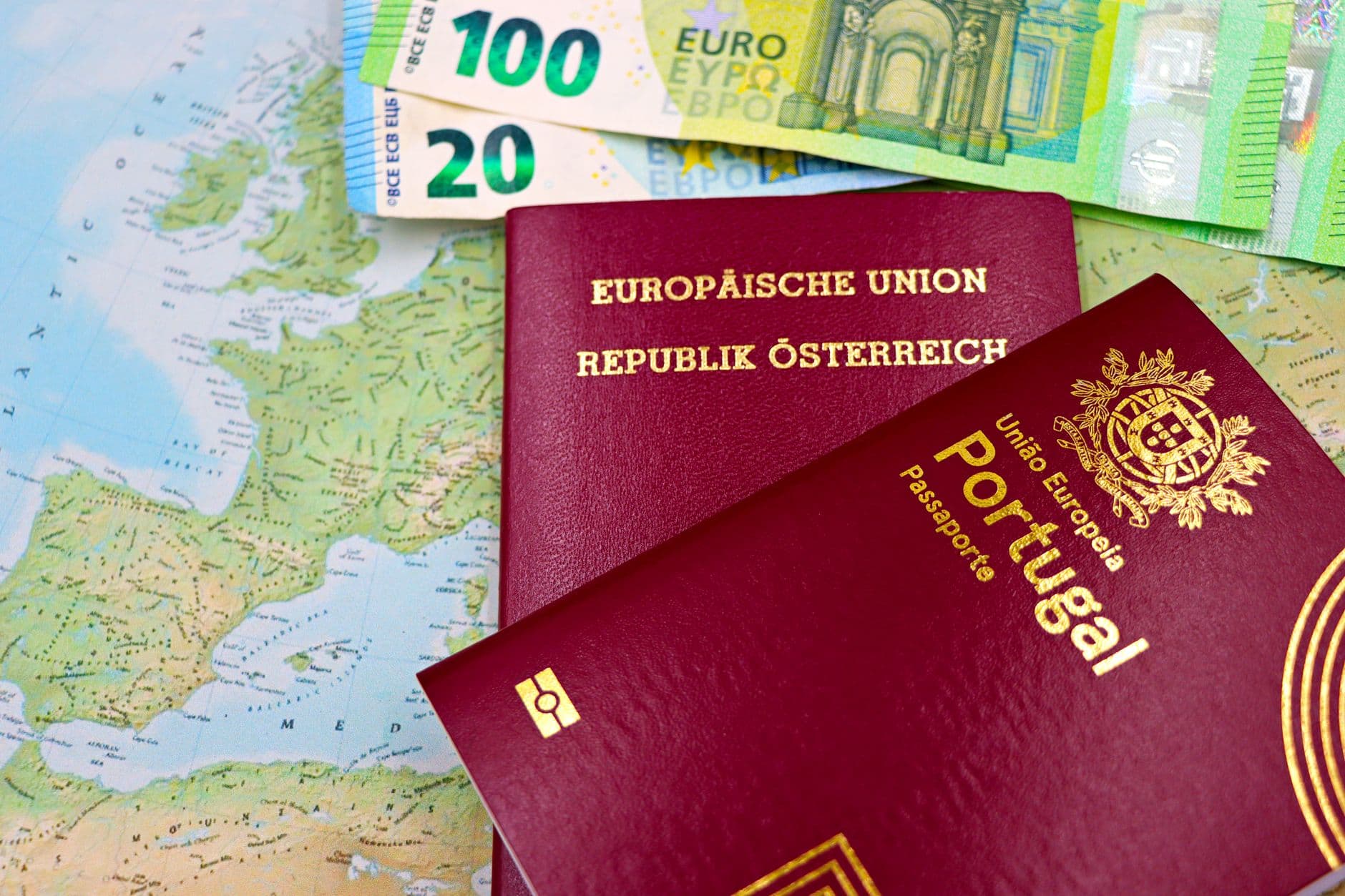 Austrian and Portuguese passports on a European map with euro banknotes.