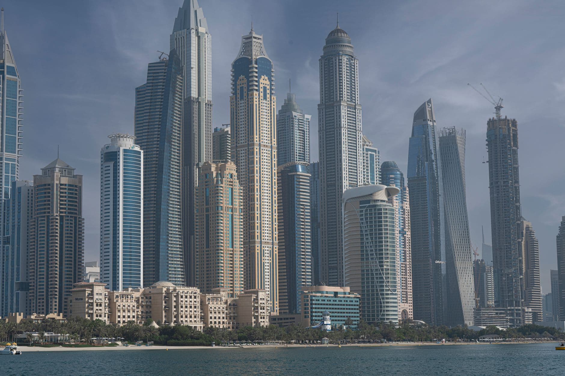 Stunning view of Dubai Marina with modern skyscrapers under a clear blue sky reflecting on the water.