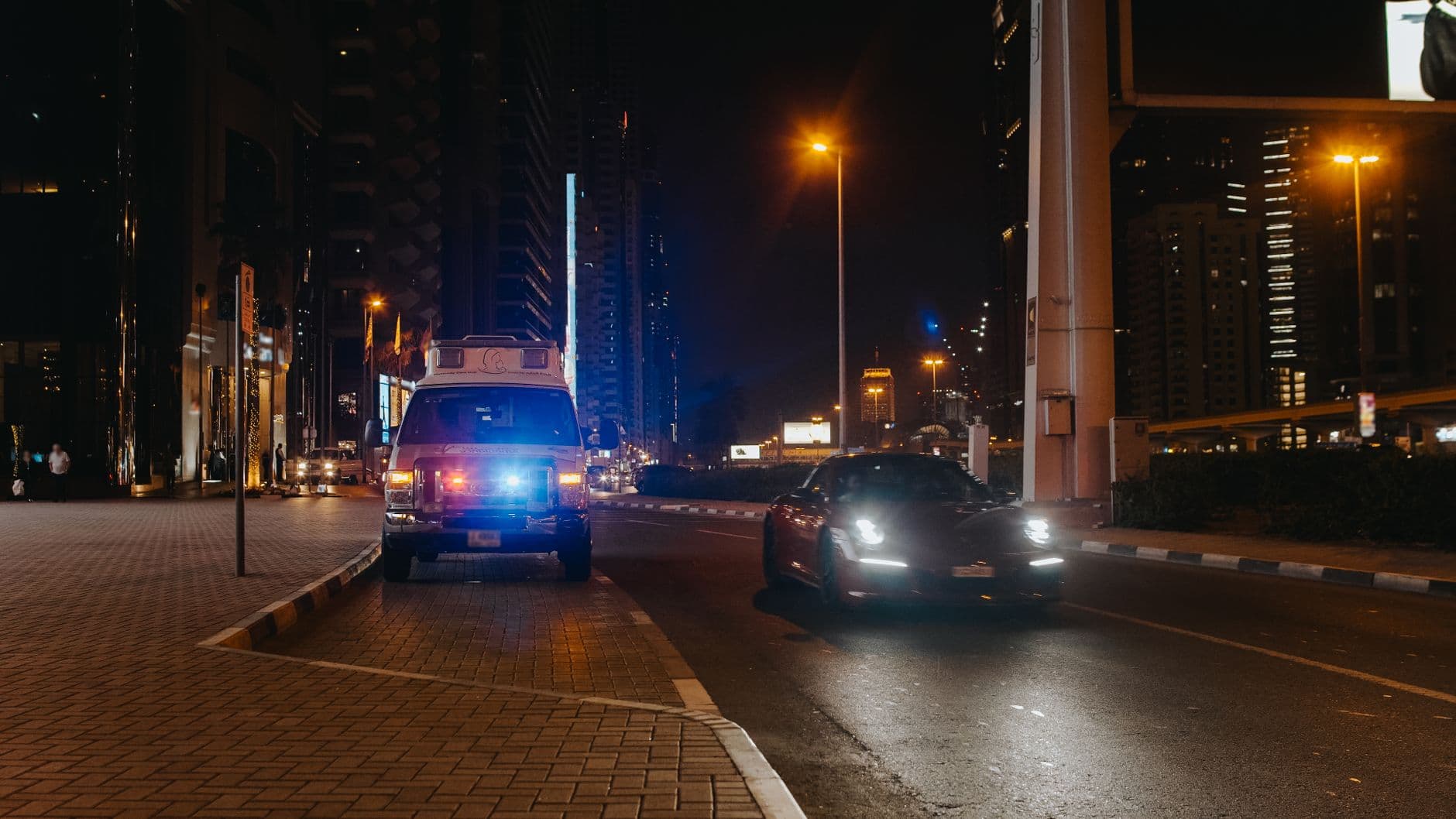 Urban night scene of a city street featuring vehicles and streetlights.
